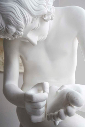 boy pulling thorn from his foot - sculpture